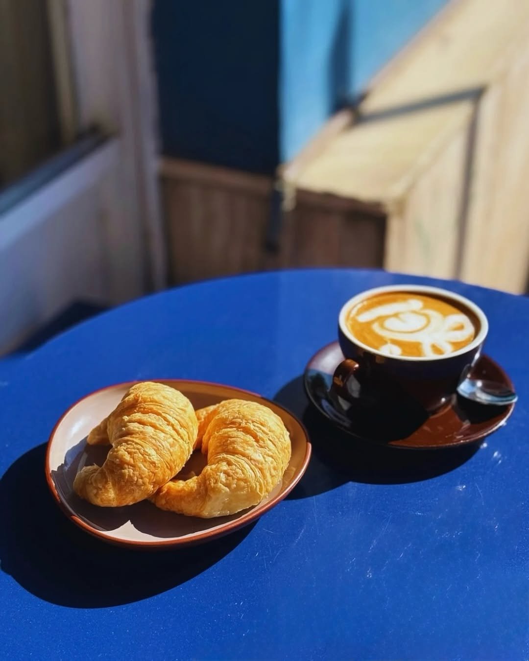 Flat white con latte art y medialunas al sol